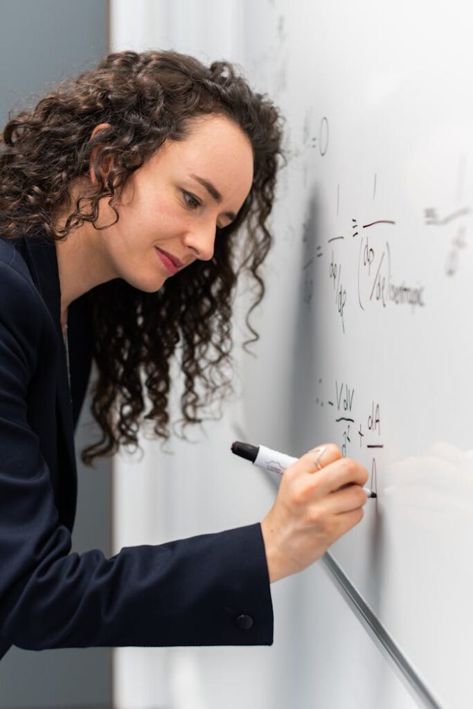 pexels photo 3862126 Female engineer solving equations on whiteboard with focus and precision.