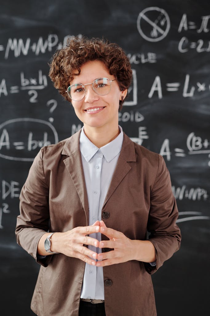 Foto von Max Fischer Teacher standing by a blackboard with algebra equations, smiling confidently.